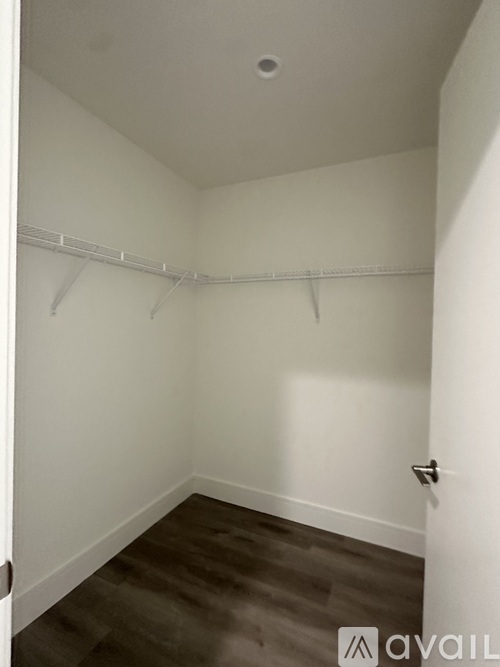 A small, empty room with a door on the right and a wall-mounted coat rack.