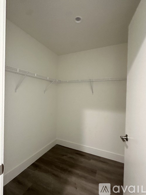 A small, empty room with a door on the right and a wall-mounted coat rack.