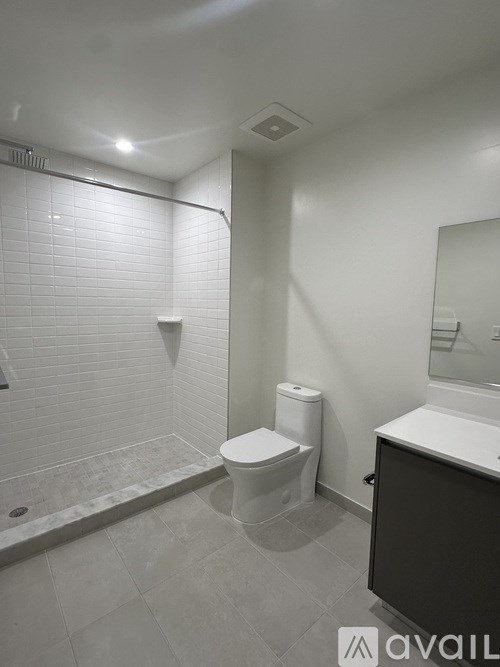 A white toilet in a small bathroom with a white tiled shower.