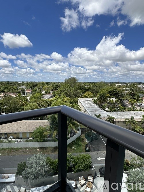 A balcony overlooks a residential area with houses and trees.
