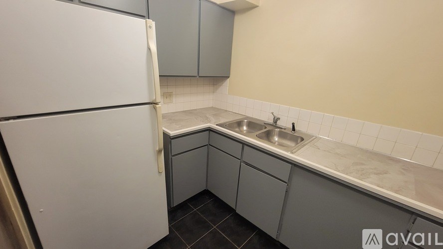 A kitchen with a white refrigerator and a sink with a marble countertop.