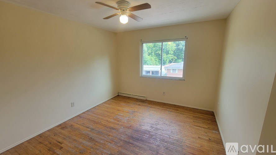A room with a ceiling fan and wooden flooring.