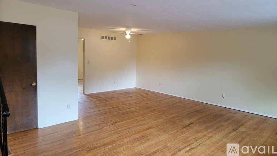 A room with wooden flooring and a door on the left.