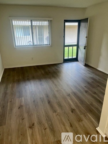 A room with wooden flooring and a door leading to a balcony.