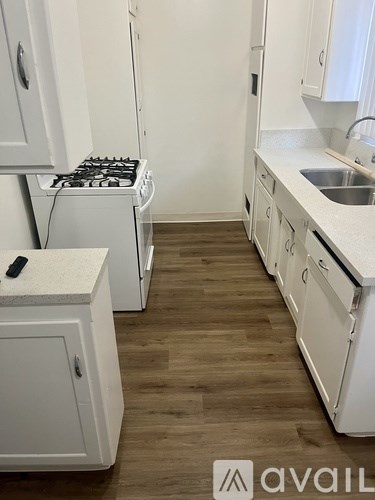 A kitchen with white cabinets and a wooden floor.