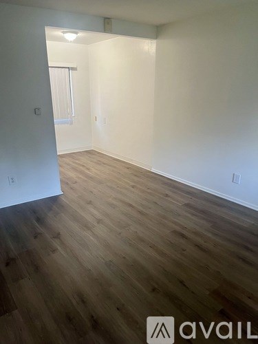 A room with wooden flooring and white walls.