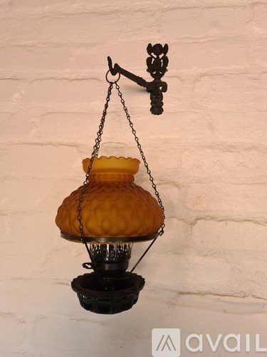 A hanging lamp with a yellow shade is suspended from a chain.