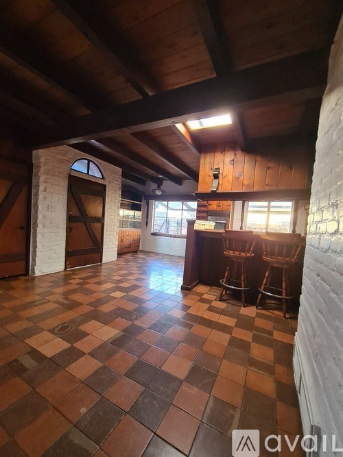 A room with a checkered floor and wooden beams on the ceiling.