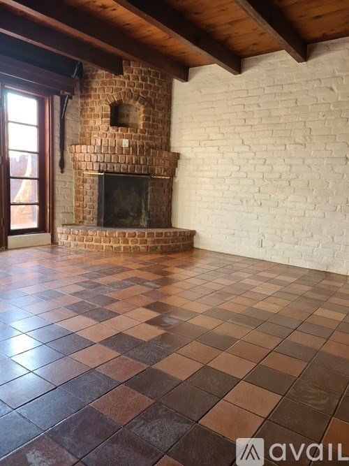 A room with a brick fireplace and a checkered floor.