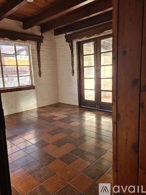 A room with a checkered tile floor and wooden beams on the ceiling.