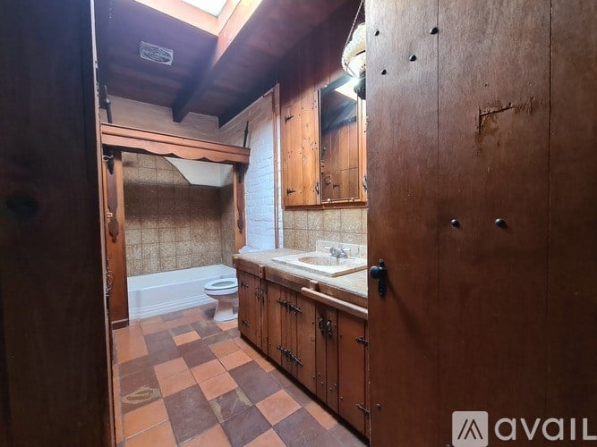 A bathroom with brown tiles and wooden cabinets.