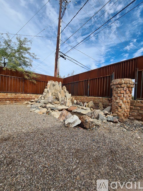 A pile of rocks sits in front of a brown fence.