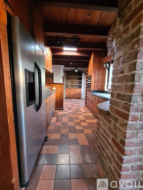 A kitchen with a refrigerator and a brick wall.