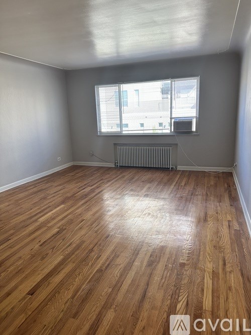 A room with wooden flooring and a window with blinds.