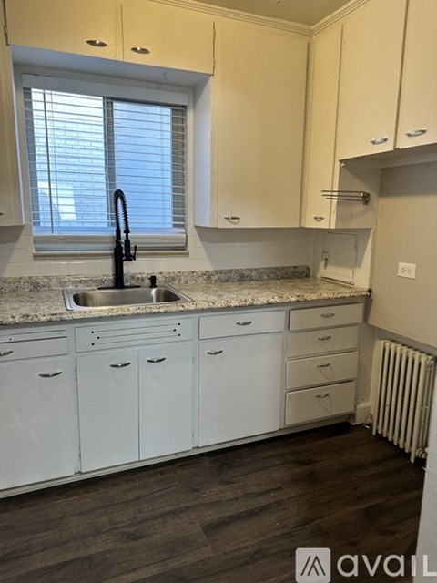 A kitchen with white cabinets and a black faucet.