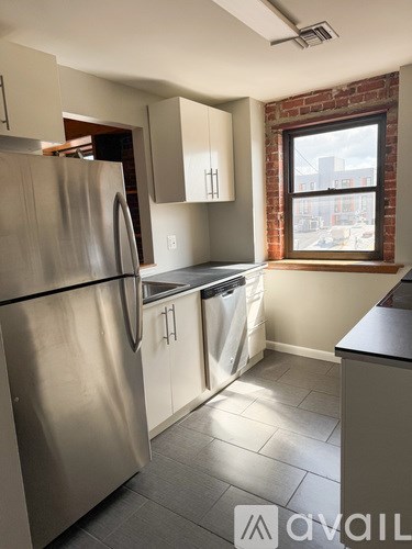 A kitchen with a stainless steel refrigerator and a window.