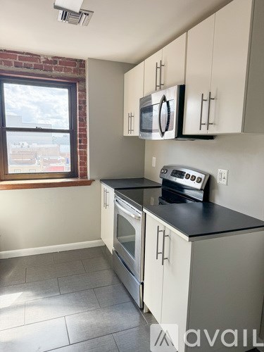 A kitchen with white cabinets and a black countertop.