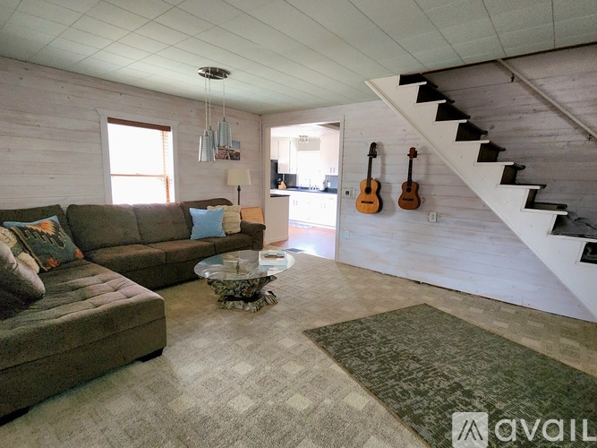 A living room with a couch, a coffee table, and a staircase.