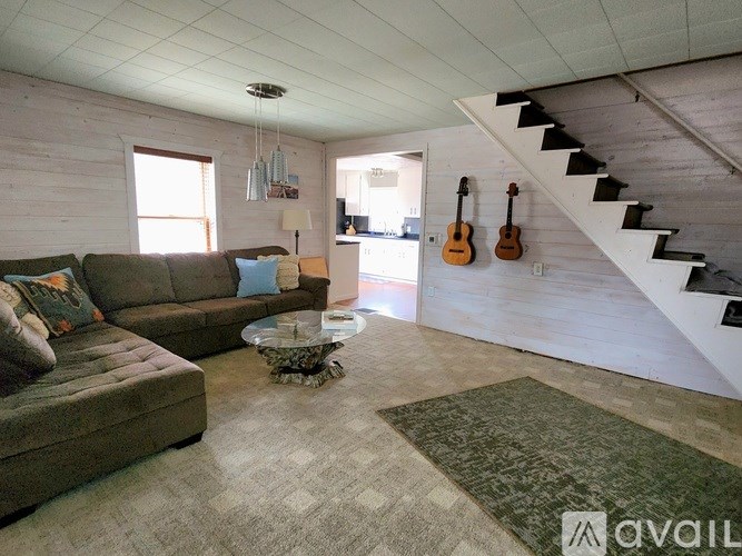 A living room with a couch, a coffee table, and a staircase.