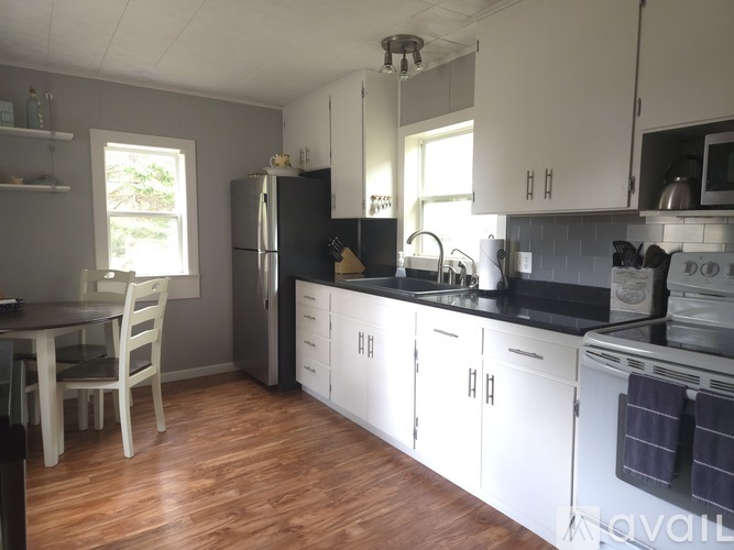 A kitchen with white cabinets and a black refrigerator.