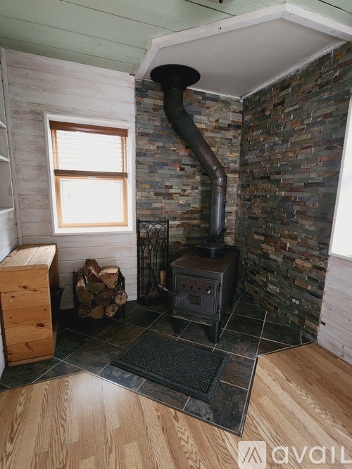A wood burning stove in a room with a stone wall.