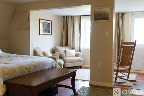 A bedroom with a bed, chair, and a painting on the wall.