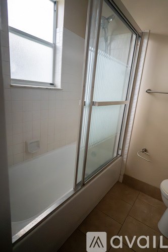 A bathroom with a glass shower door and a toilet.