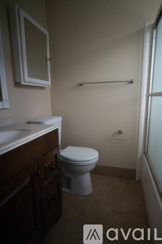 A bathroom with a toilet, sink, and a shower rod.