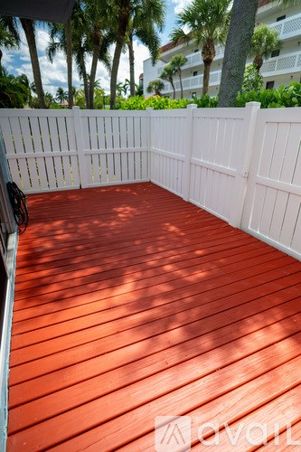 A wooden deck with a white fence and a bicycle leaning against it.