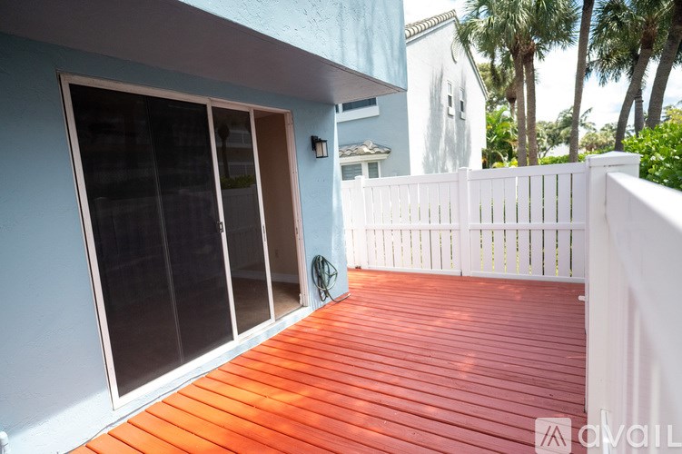 A wooden deck with a white fence and glass doors.