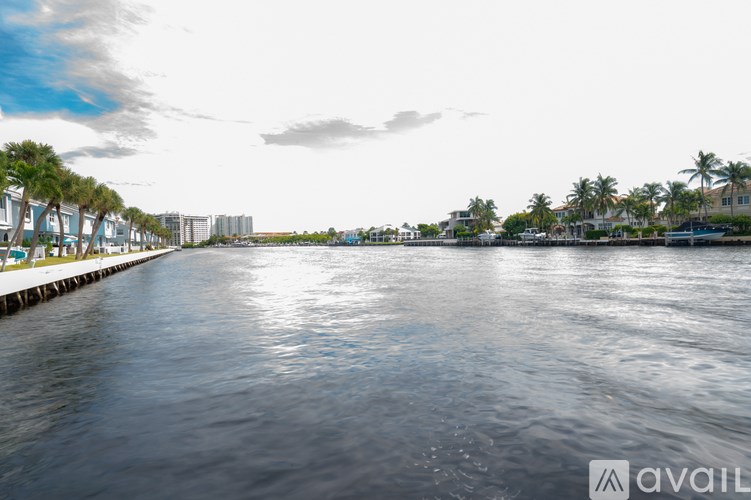 A calm body of water with a dock on the left and buildings in the distance.