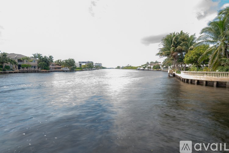 A calm river with a dock on the right side and buildings in the background.