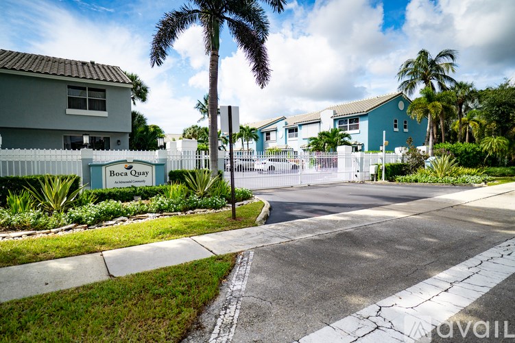 A street view of Boca Quay with a white fence and a palm tree.