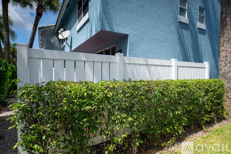 A white fence in front of a blue house.