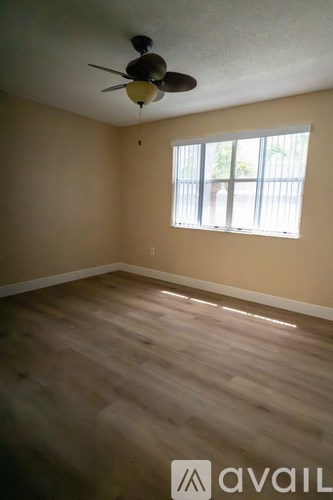 A room with a ceiling fan and wooden flooring.
