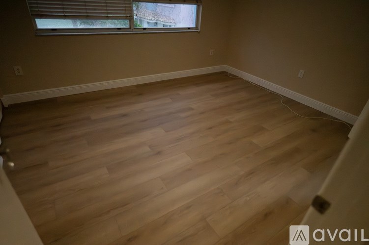 A room with wooden flooring and a window with blinds.