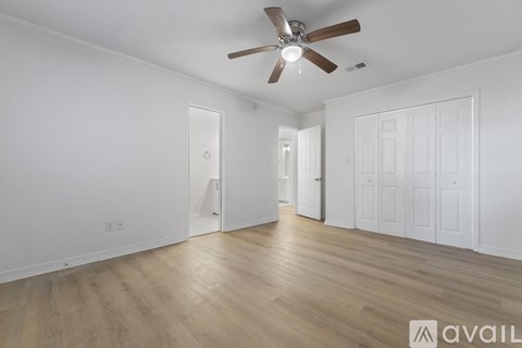 A spacious room with a ceiling fan and wooden flooring.