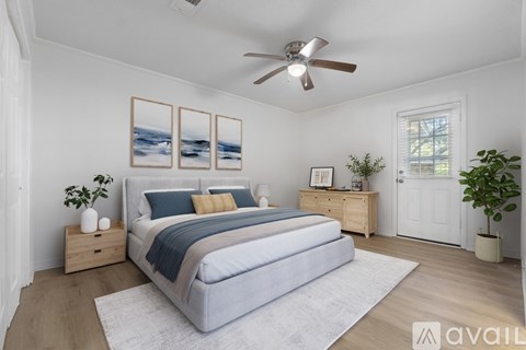 A bedroom with a large bed, a ceiling fan, and a painting on the wall.
