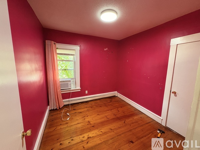 A room with a window and a wooden floor.