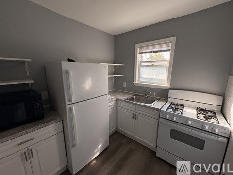 A kitchen with white appliances and wooden floors.