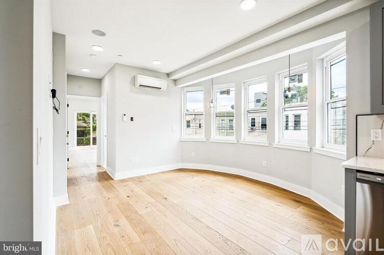 A spacious room with wooden flooring and large windows.
