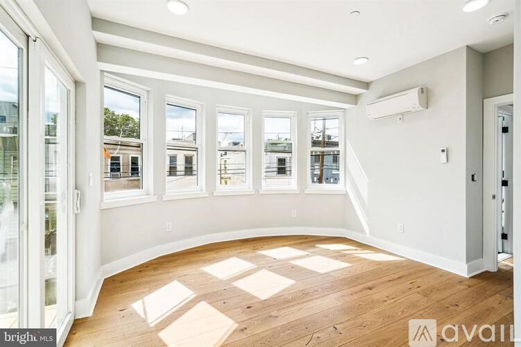 A room with wooden floors and large windows is available for rent.