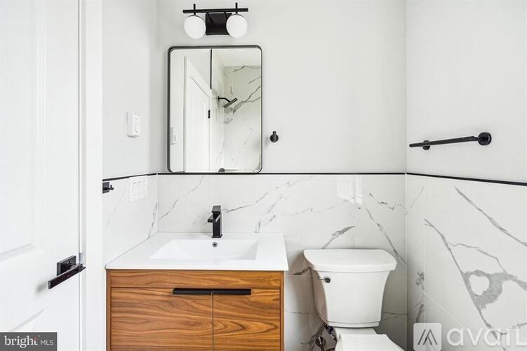 A bathroom with a marble counter top and a wooden drawer under a mirror.