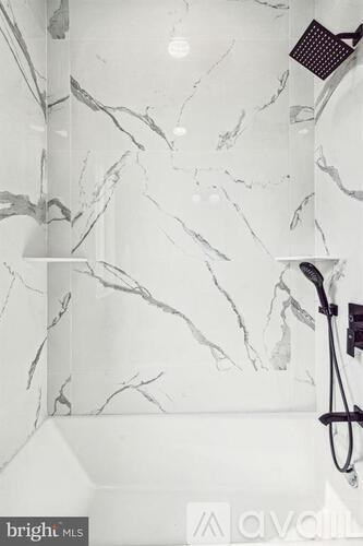 A bathroom with a marble wall and a shower head.