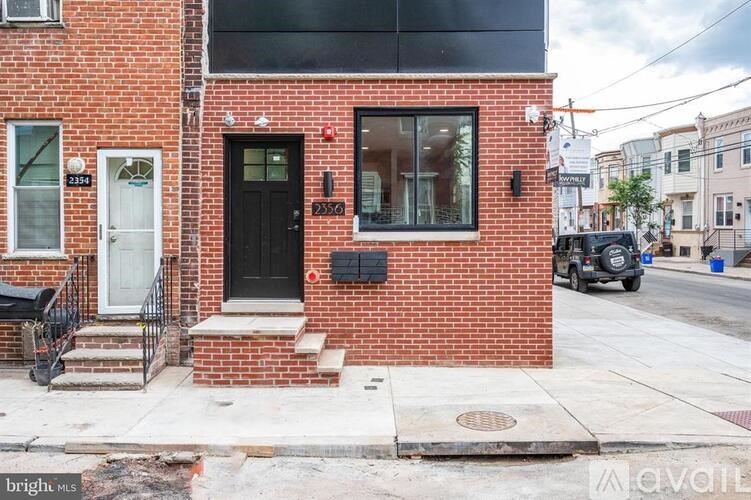 A red brick house with a black door and a window with a black frame.