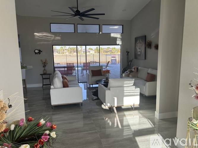 A living room with white furniture and a ceiling fan.