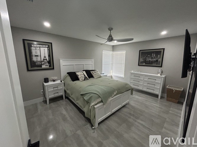 A bedroom with a bed, nightstand, and a ceiling fan.