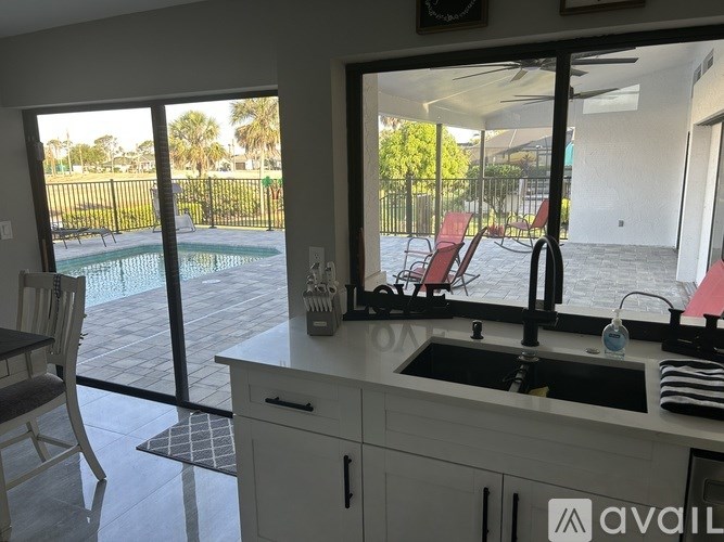 A kitchen with a sink and a window overlooking a pool.