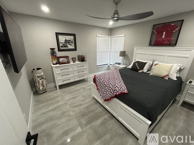 A bedroom with a bed, dresser, and ceiling fan.