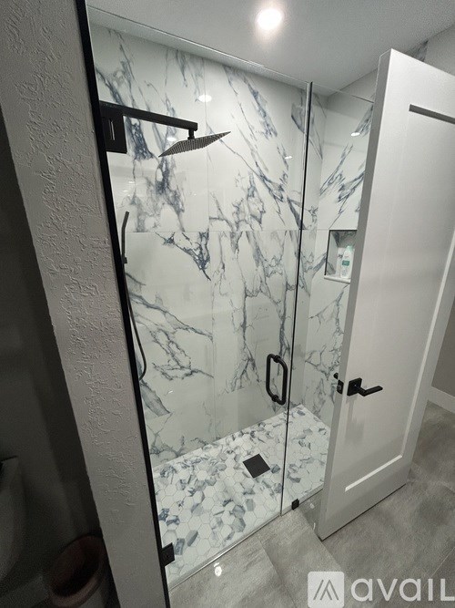 A bathroom with a marble wall and a glass shower door.